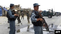 Afghan policemen stand guard as two US soldiers (C) arrive at the site of a twin suicide attack near NATO's Kandahar Air Base, June 6, 2012.