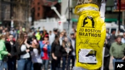 游客2013年4月27日在马萨诸塞州波士顿科普利广场为波士顿马拉松爆炸案受害者临时搭建的一个纪念牌前留步观看