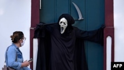 8月7日，巴西富米加一女子觀看演員法比奧·德阿梅達扮演死神提請公眾主義戴口罩和保持社交距離以防範病毒傳播的重要性。