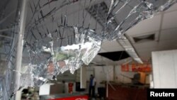 卡拉卡斯社区遭到哄抢后，可以看到一个便利店破损的窗户(2017年4月21日)