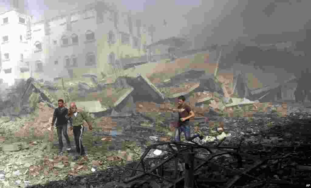 2012年11月18日，在以色列对加沙市发动一次空袭后，巴勒斯坦人匆匆逃离一座受损建筑。