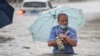 TOPSHOT - This photo taken on July 20, 2021 shows a man wading through flood waters along a street following heavy rains in Zhengzhou in China's central Henan province. (Photo by STR / AFP) / China OUT