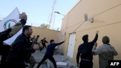 伊拉克示威者衝擊美國駐巴格達大使館的外牆，抗議者譴責美國對伊拉克境內伊朗支持的民兵發動空襲。2019年12月31日，法新社照片）