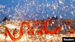 2013年2月10日在北京的一处游乐园庆祝农历新年的火龙舞表演中，火龙队员在铁水花与干花的施放中舞着火龙