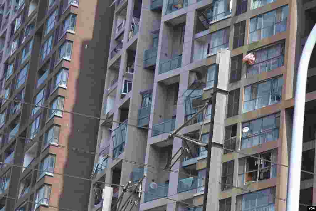 天津爆炸事故现场，核心爆炸区周围多座居民楼窗户被震碎，高速公路桥梁受损，多辆大货车被炸翻，小汽车起火或被砸，多名当地居民仍逗留在事故现场。（美国之音记者东方拍摄）