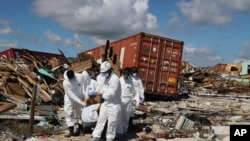 A Bahamas coroners team carries a body out of The Mudd neighborhood in the Marsh Harbor area of Abaco Island in the Bahamas in the aftermath of Hurricane Dorian, Sept. 9, 2019. 