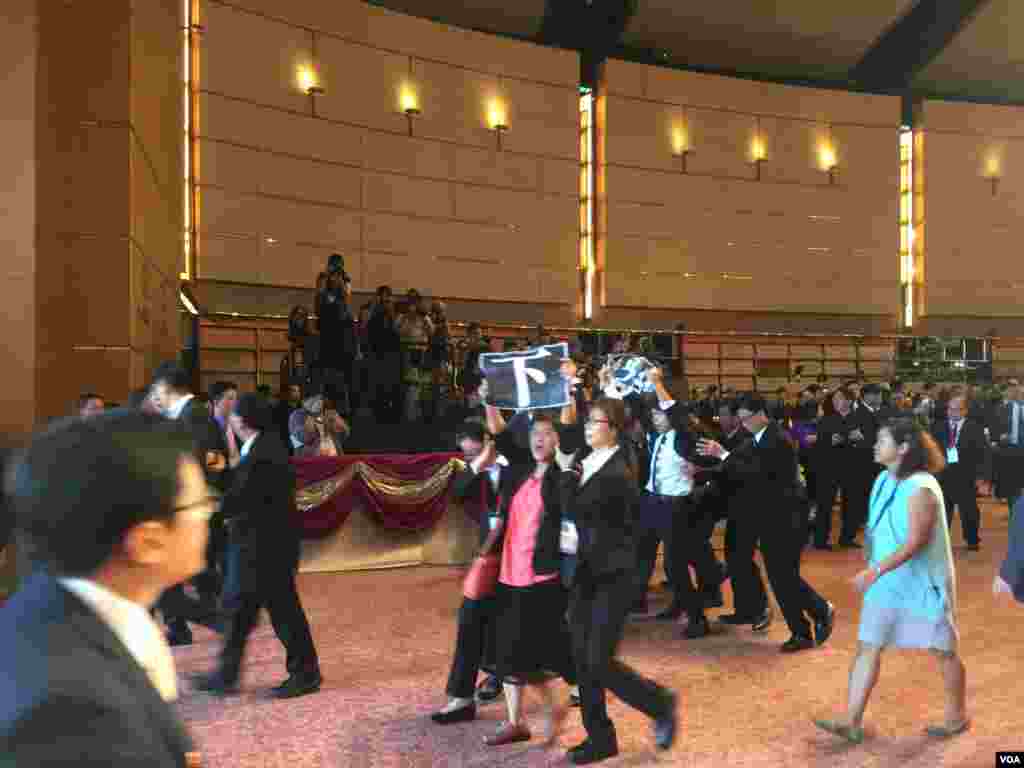 香港特区政府星期六在会展中心举办国庆67周年大型酒会。在特首梁振英开始致辞后，参加酒会的多位候任民主党立法会议员，举起反梁标牌和单张，高喊梁振英下台的口号，被大批保安人员带出会场。(美国之音海彦拍摄)