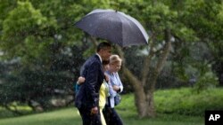 奥巴马总统走下直升机后，为白宫高级顾问瓦莱丽·贾勒特和白宫办公厅副主任安妮塔·布瑞克瑞撑伞，一道返回白宫椭圆形办公室。（2015年5月18日）