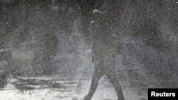 2014年1月6日，在伊利诺伊州芝加哥市，一位女士冒着刺骨的寒风走上街头，冷风迎面吹来，扬起积雪，遮挡住视线。