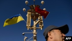 資料照：一名男子走過北京天安門廣場燈柱上懸掛的中國與烏克蘭國旗。 （2013年12月5日）