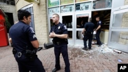 2016年9月22日，美國北卡夏洛特市，警察站在一個被抗議人群砸毀的店舖前面。