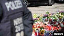 ເຈົ້າ​ໜ້າ​ທີ່​ຕຳຫຼວດ​ຢືນ​ຢູ່​ໃກ້​ກັບ​ດອກ​ໄມ້​ທີ່​ວາງ​ໄວ້​ຢູ່​ສະ​ຖານ​ທີ່​ທີ່​ສາມ​ຄົນ​ຖືກ​ຂ້າ​ຕາຍ ແລະ ຫຼາຍ​ຄົນ​ໄດ້​ຮັບ​ບາດ​ເຈັບ​ໃນ​ການ​ໂຈມ​ຕີ​ໃຊ້​ມີດ​ແທງ​ຢູ່​ງານ​ເທດ​ສະ​ການ​ແຫ່ງ​ນຶ່ງ​ໃນ​ເມືອງ ໂຊ​ລິງ​ເກັນ, ເຢຍ​ຣະ​ມັນ, 26 ສິງ​ຫາ 2024.