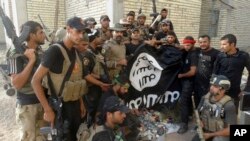 Iraqi security forces backed by Shiite and Sunni pro-government fighters celebrate as they hold a flag of the Islamic State militant group they captured in Anbar University in Ramadi, Anbar province, Iraq, July 26, 2015.