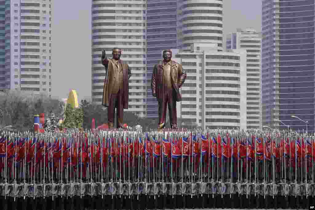 朝鲜学生举着国旗，簇拥着前领袖金日成、金正日的铜像，参加阅兵（2017年4月15日）