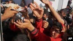 2014年8月12日，失去家园的雅兹迪教徒聚集在叙利亚的一个难民营领取食物