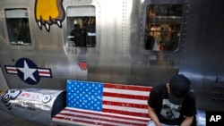 一位男士坐在北京某家出售美國名牌服裝的時尚精品店外繪有美國國旗圖案的長椅上看手機。(2019年5月13日)