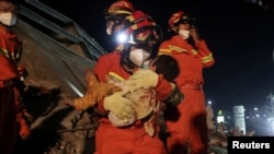 一名搜救人员从福建省泉州市欣佳酒店的坍塌废墟中救出一名儿童。（2020年3月8日）