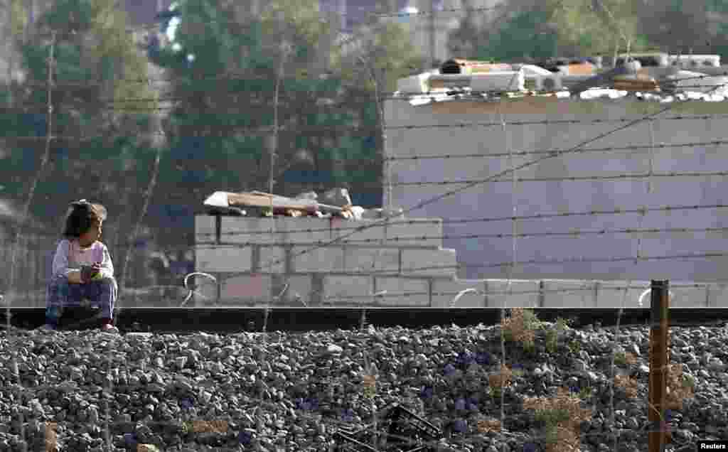 A girl sits on a railway track as she looks to cross the border fence from Ras al-Ain into Turkey, November 20, 2012.