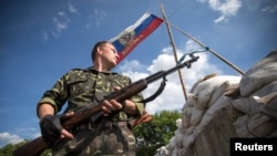 2014年6月24日一名亲俄分离分子在东乌卢甘茨克地区的里斯坦斯克镇外路上的检查哨警戒。