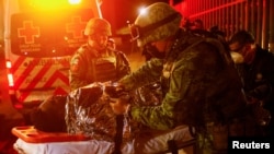 墨西哥消防人員在華雷斯城移民設施發生火災後在現場救治傷員。（2023年3月28日）