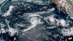 ພາບ​ຈາກ​ດາວ​ທຽມ​ໂດຍ​ອົງ​ການ​ຄຸ້ມ​ຄອງ​ຊັ້ນ​ບັນ​ຍາ​ກາດ ແລະ ມະ​ຫາ​ສະ​ໝຸດ​ແຫ່ງ​ຊາດ ສະ​ແດງ​ໃຫ້​ເຫັນພາ​ຍຸ​ເຮີ​ຣິ​ເຄນ ກິ​ລ​ມາ ແລະ ພາ​ຍຸ​ລະ​ດູ​ຮ້ອນ​ຊື່​ວ່າ ໂຮນ, ຢູ່​ພາກ​ຕາ​ເວັນ​ຕົກ-ຕາ​ເວັນ​ຕົກ​ສຽງ​ໃຕ້​ຂອງ​ແຫຼມ ບາ​ຈາ ຄາ​ລິ​ຟໍ​ເນຍ, ປະ​ເທດ ເມັກ​ຊິ​ໂກ, 22 ສິງ​ຫາ 2024. NOAA via AP)