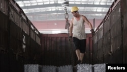 一名工人在河北唐山一家仓库里往卡车上装钢筋 (2015年路透社资料照)
