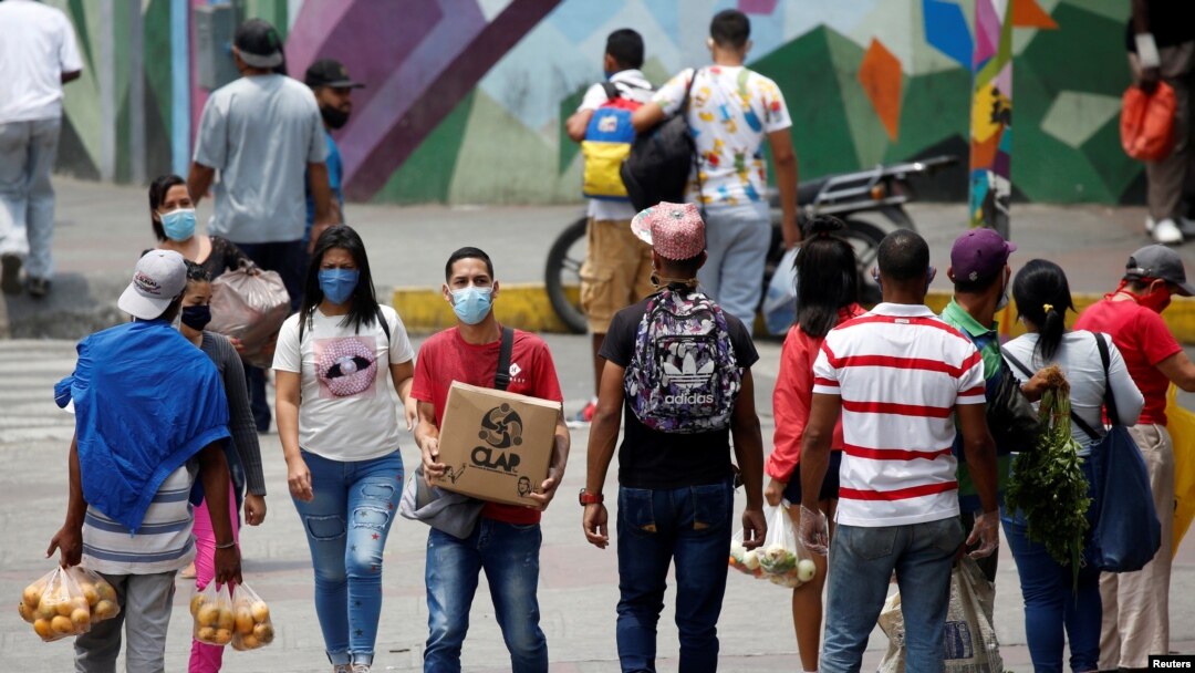 Las personas con tapabocas caminan cerca de los vendedores ambulantes en Petare, Caracas. Abril 20, 2020.