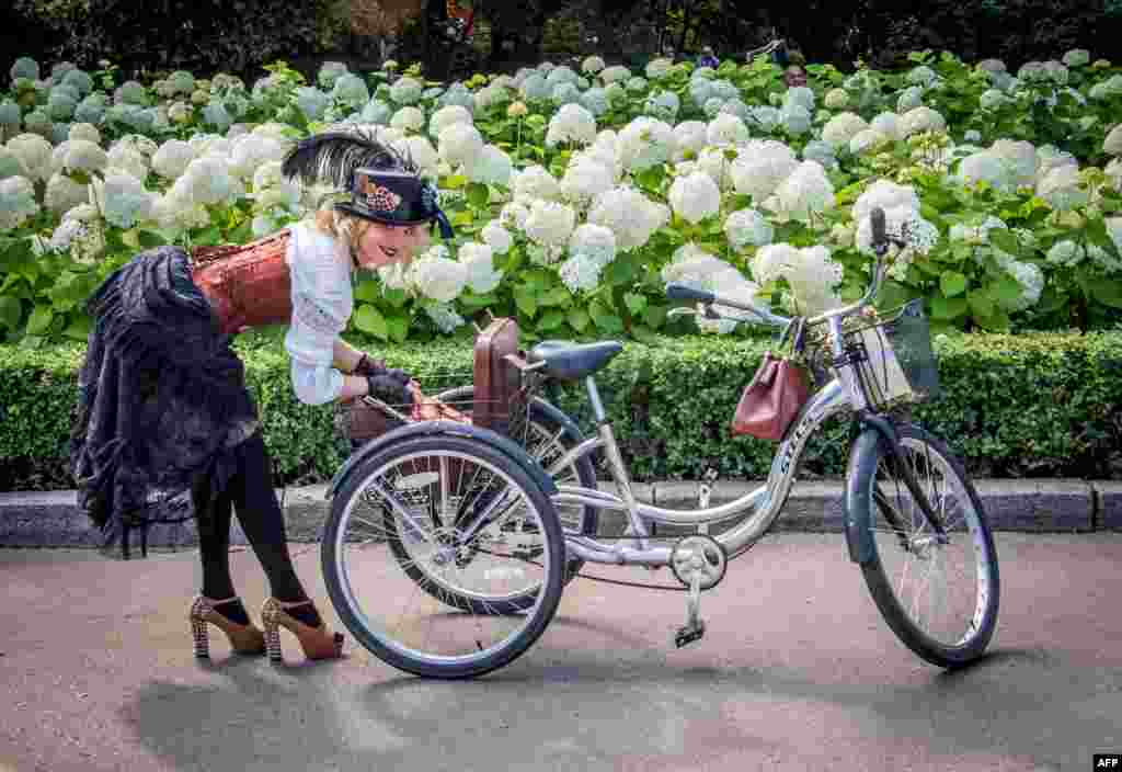 在莫斯科的索科尔尼基公园，第五届&ldquo;女士骑自行车节&rdquo;活动的参与者从三轮车后篮中拿东西。该节日的目的是展示城市时尚女性和复古风格的自行车 （2017年8月6日）
