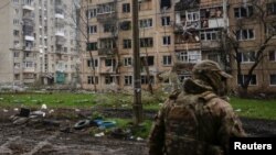 2023年4月21日，在烏克蘭頓涅茨克地區的前線城鎮巴赫穆特，一名烏克蘭軍人走在被俄羅斯軍事打擊破壞的居民樓前。