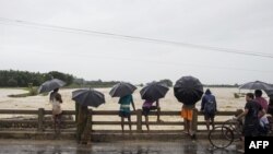 wasu 'yan kasar Nepal a wani kauye suke kallon ruwa na gudu.