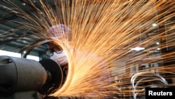 浙江杭州市一名戴著口罩的工人在生產自行車輪子鋼圈的生產線上工作。（2020年3月2日）