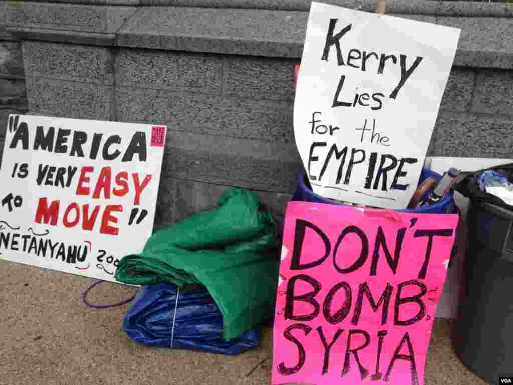 右上角的白色标语指称美国国务卿克里为帝国撒谎。下角的粉红色标语呼吁不要轰炸叙利亚。左下角的白色标语指称美国很容易被左右。（美国之音 龚小夏拍摄）