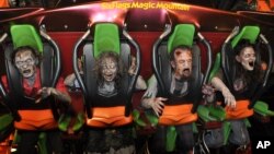 ປະ​ຊາ​ຊົນ​ແຕ່ງ​ຕົວ​ເປັນ​ຜູ້​ຂີ່​ລົດ​ໄຟ​ລອຍ​ຟ້າ​ຢູ່​ສວນ​ສະ​ໜຸກ SixFlags ໃນ​ວັນ ຮາ​ໂລ​ວີນ. (Photo: Business Wire)