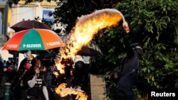 ແຟ້ມຮູບ-ຜູ້ປະທ້ວງຕໍ່ຕ້ານລັດຖະບານຄົນນຶ່ງ ແກ່ວງລະເບີດໄຟເຂົ້າໃສ່ສະຖານີຕໍາຫຼວດ ຊິມ ຊາ ສຸຍ (Tsim Sha Tsui) ລະຫວ່າງການປະທ້ວງໃນຮົງກົງ, ວັນທີ 20 ຕຸລາ 2019. 