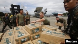 美国和菲律宾两国军人向一架美军C-130运输机上装运救灾物资，帮助菲律宾中部的台风灾民。