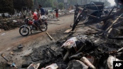 埃及人骑摩托路过开罗大学附近的纳达广场，地上是被烧毁的穆尔西画像。