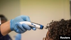 美國海關邊防人員為從非洲進入美國的理由人士進行體溫檢測。