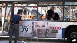 以色列警察11月21日在特拉维夫一个爆炸的地点检查受到损坏的巴士