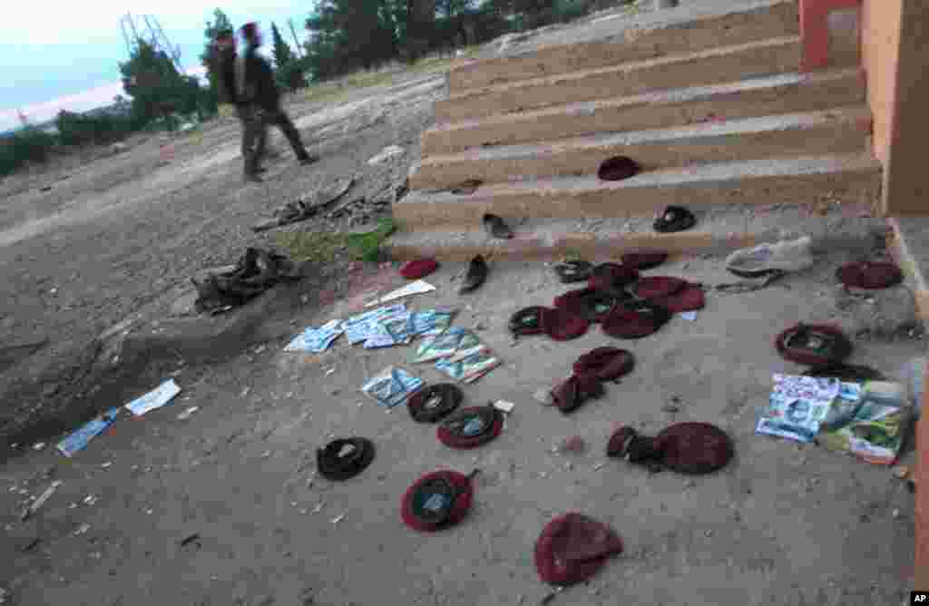 Syrian fighters stand guard in front of a destroyed building at a military base they took over from the Syrian army in Aleppo, November 19, 2012. 