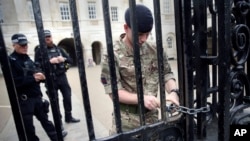 一名军人9月16日给怀特霍尔宫皇家骑兵卫队的铁门上锁。伦敦帕森斯·格林地铁站一节车厢星期五发生爆炸。