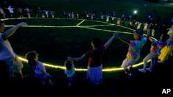 2019年8月15日在1969年伍德斯托克音乐和艺术博览会原址人们围着一个大而明亮的和平标志围成一圈。