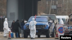 北京房山地區發現非洲豬瘟後，身穿防護服的防疫人員在通往出現疫情的村莊道路上設卡。 （2018年11月23日）