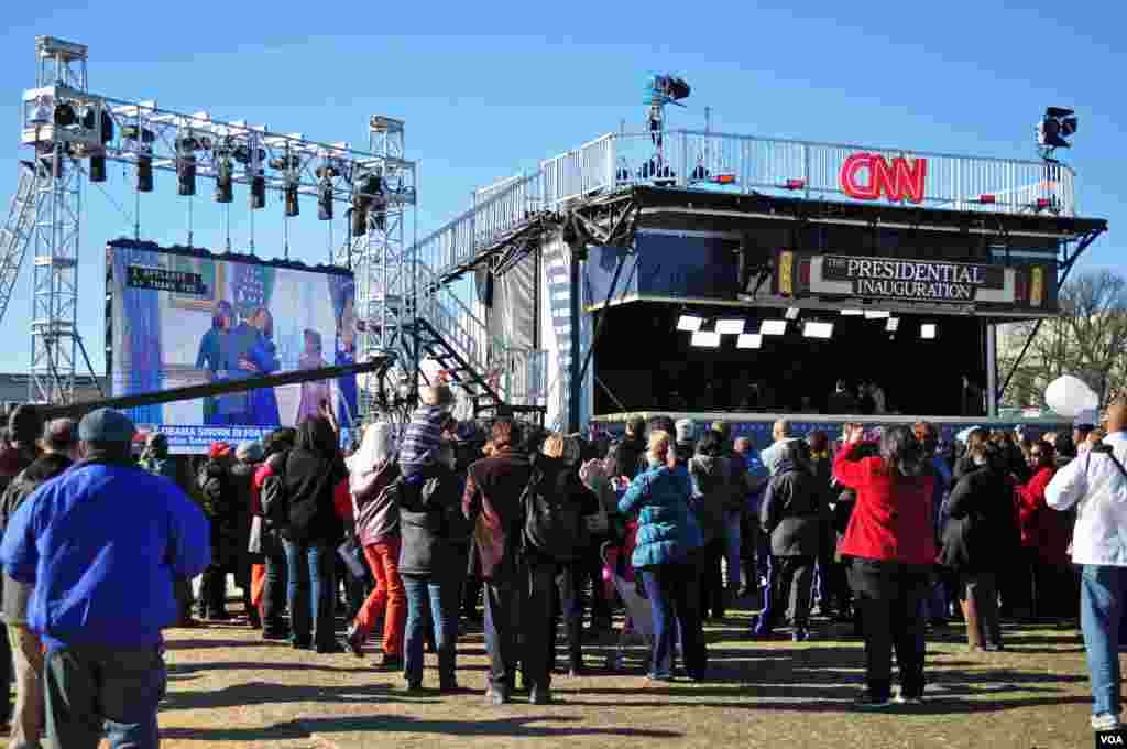 人们在国会大草坪通过巨大的电视屏幕观看奥巴马总统在白宫小范围宣誓就职的情景。(VOA / D. Manis）