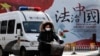 A woman and a police van pass a Chinese government propaganda billboard that reads "China Rule By Law" on a street in Beijing, Dec. 28, 2016. Infuriated by a decision by Beijing prosecutors to drop charges in a high-profile police brutality case, universi