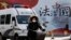 A woman and a police van pass a Chinese government propaganda billboard that reads "China Rule By Law" on a street in Beijing, Dec. 28, 2016. Infuriated by a decision by Beijing prosecutors to drop charges in a high-profile police brutality case, universi