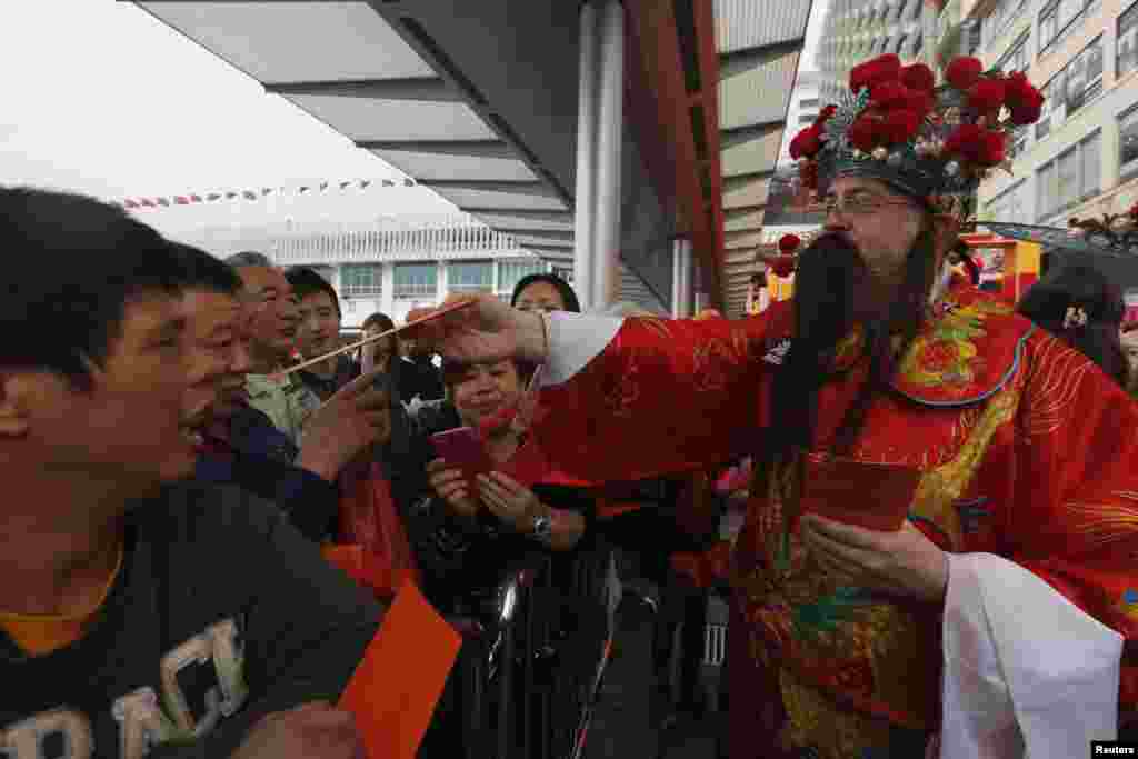 在香港一个购物中心，有人装扮财神给人们发红包（2015年2月23日）