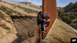 2018年12月22日洪都拉斯移民幫助他兒子攀登美國邊境圍欄從墨西哥蒂華納進入美國加利福尼亞州圣迭戈