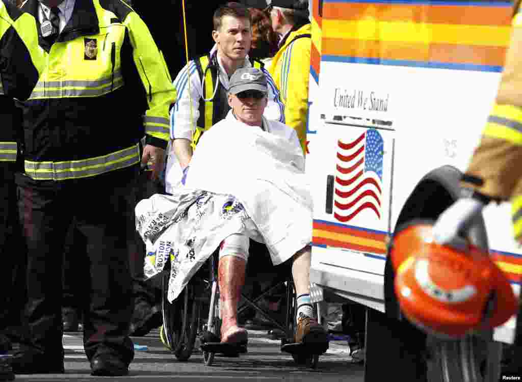人们用轮椅把一名受伤的跑步选手送离医疗鉴定帐篷。