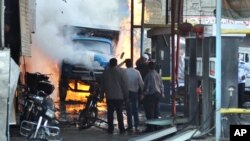 敘利亞官方11月28日發佈的圖片顯示﹐民眾在傑馬納圍觀一輛遭汽車炸彈爆炸後燃燒中的卡車。