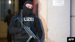 2014年1月16日，一名德国警官在柏林的一栋公寓对极端分子嫌疑人的住处进行搜查后站在这栋公寓外面站岗。